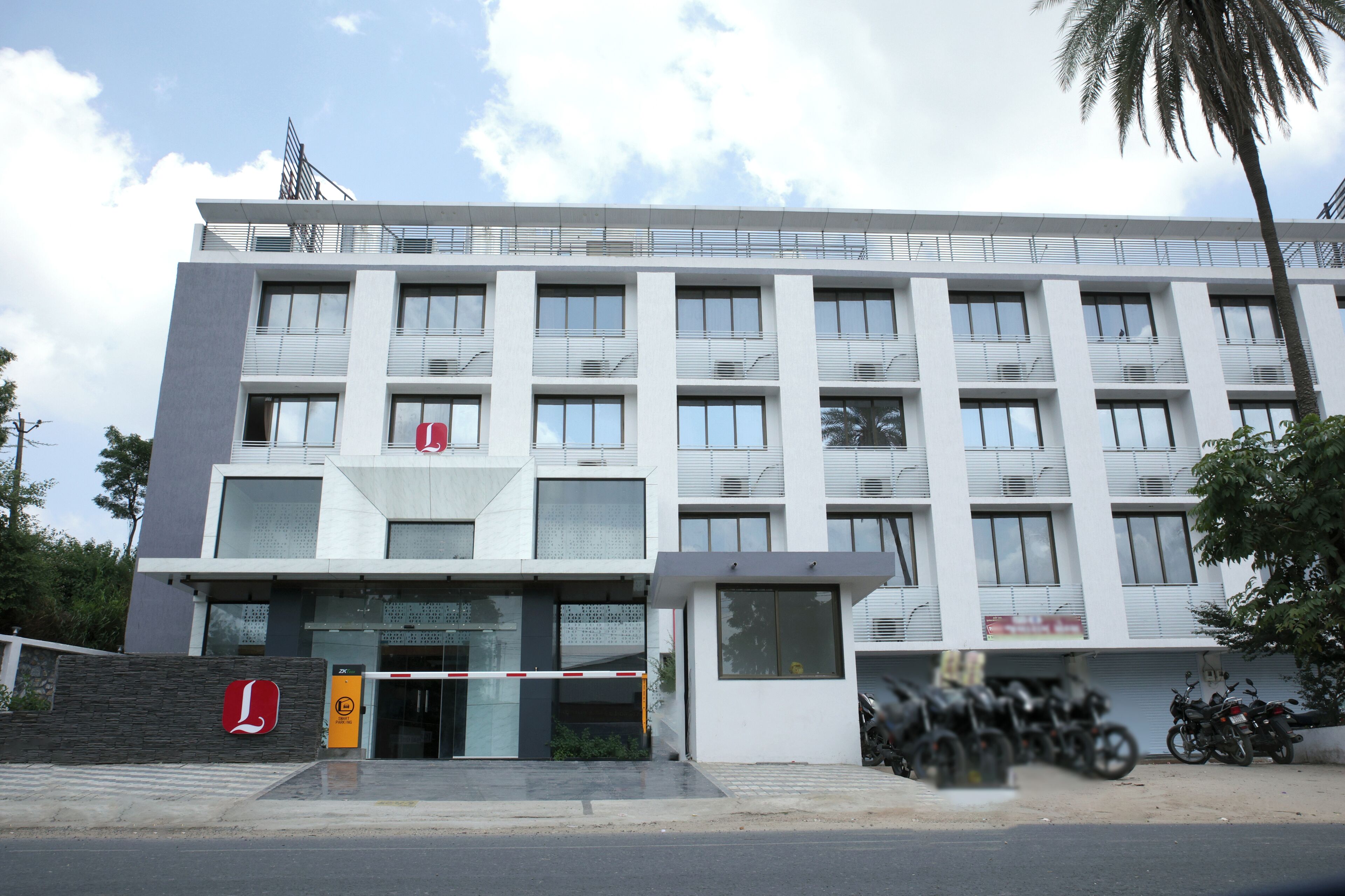 A modern building with a flat roof, multiple windows, and a gated entrance.