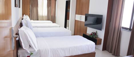 Habitación de hotel con dos camas, televisión, paneles de madera y una ventana con cortinas.