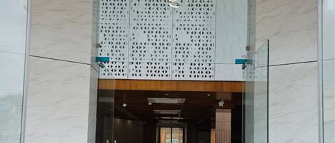 A modern entrance with glass doors, a marble floor, and a wooden ceiling.