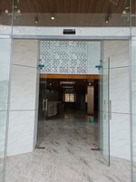 A modern entrance with glass doors, a marble floor, and a wooden ceiling.