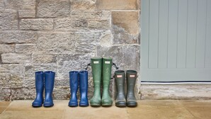 A row of rubber boots against a stone wall.