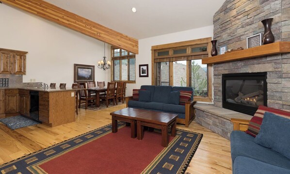 A spacious living room with a fireplace, a dining area, and a kitchen.