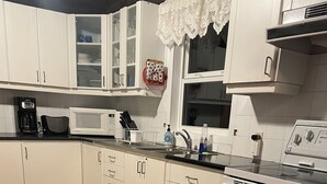 Une cuisine avec des meubles blancs, un four à micro-ondes, une cuisinière et un évier.
