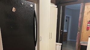 Une cuisine avec un réfrigérateur noir, un congélateur blanc et un plancher en bois.