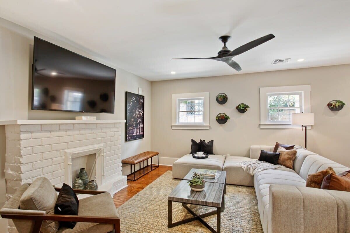 A living room with a fireplace, sofa, coffee table, and a TV mounted on the wall.