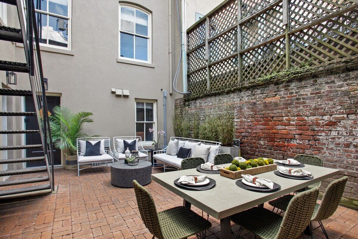 Eine Terrasse mit Esstisch, gedeckt für vier Personen, umgeben von Korbstühlen und einer gepolsterten Couch.