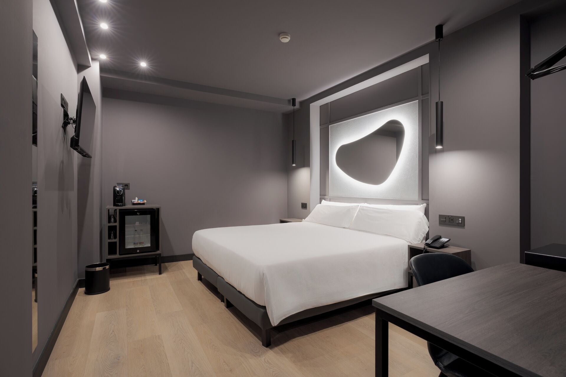 A modern bedroom with a bed, bedside table, and a desk.