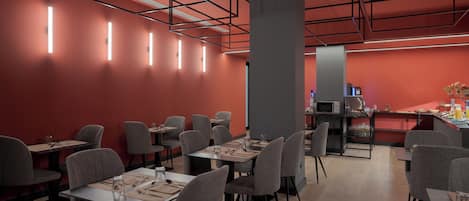 Ein modernes Restaurant mit roten Wänden, grauen Stühlen und gedeckten Tischen.