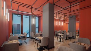 A modern dining area with multiple tables and chairs, large windows, and a geometric ceiling design. - Hotel LIVVO La Escarlata (Las Palmas de Gran Canaria)