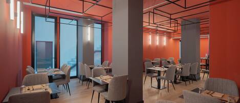 A modern dining area with multiple tables and chairs, large windows, and a geometric ceiling design.