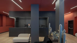 A modern reception area with a receptionist desk, a white sofa, a black armchair, and a cactus display. - Hotel LIVVO La Escarlata (Las Palmas de Gran Canaria)