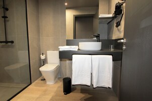 Ein modernes Badezimmer mit Duschkabine aus Glas, einer weißen Toilette, einem großzügigen weißen Waschbecken und einem Handtuchhalter mit zwei Handtüchern.