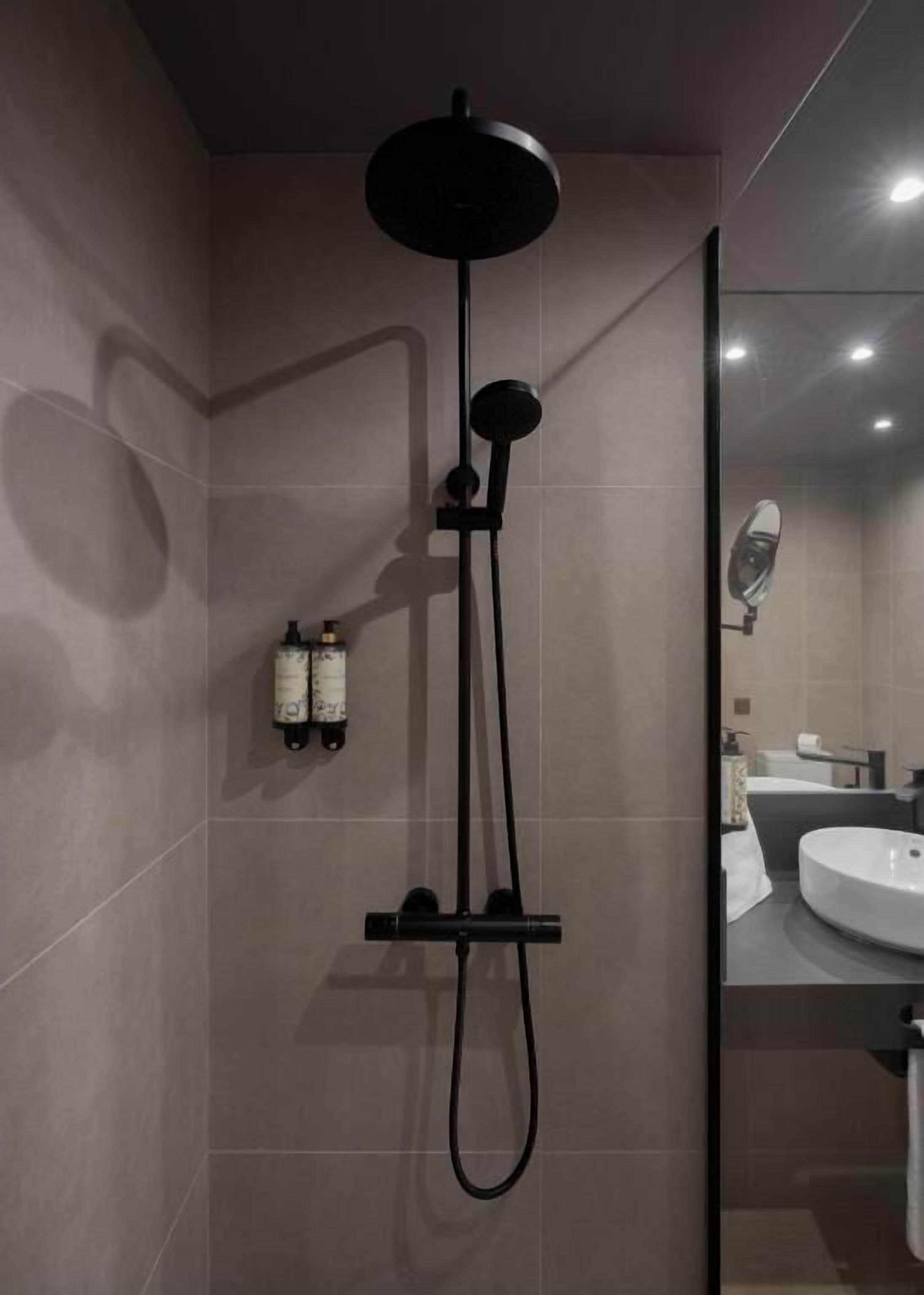 Un bagno moderno con doccia, lavandino e specchio.