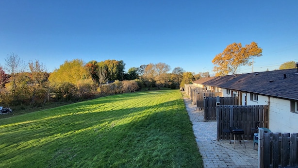 A row of wooden houses with a paved pathway and a grassy area. - Happyland Inn (Severn)