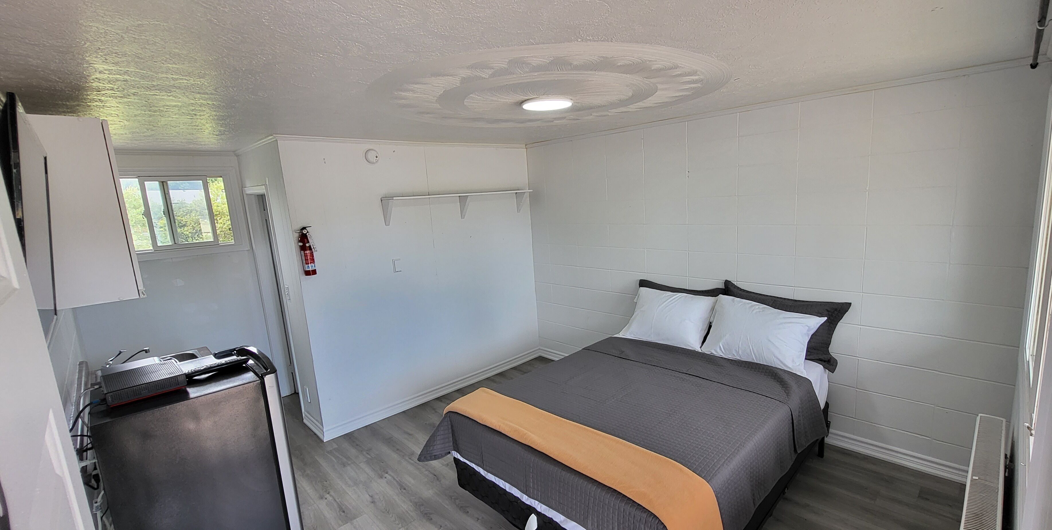 Un dormitorio con cama, escritorio y ventana.
