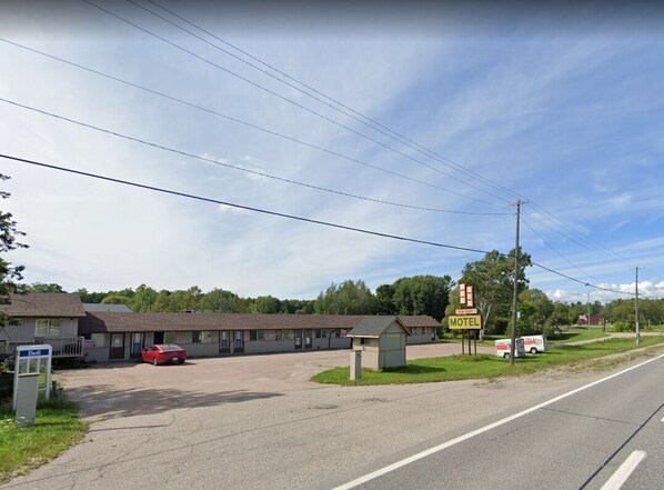 Un motel con un estacionamiento amplio y un edificio pequeño.