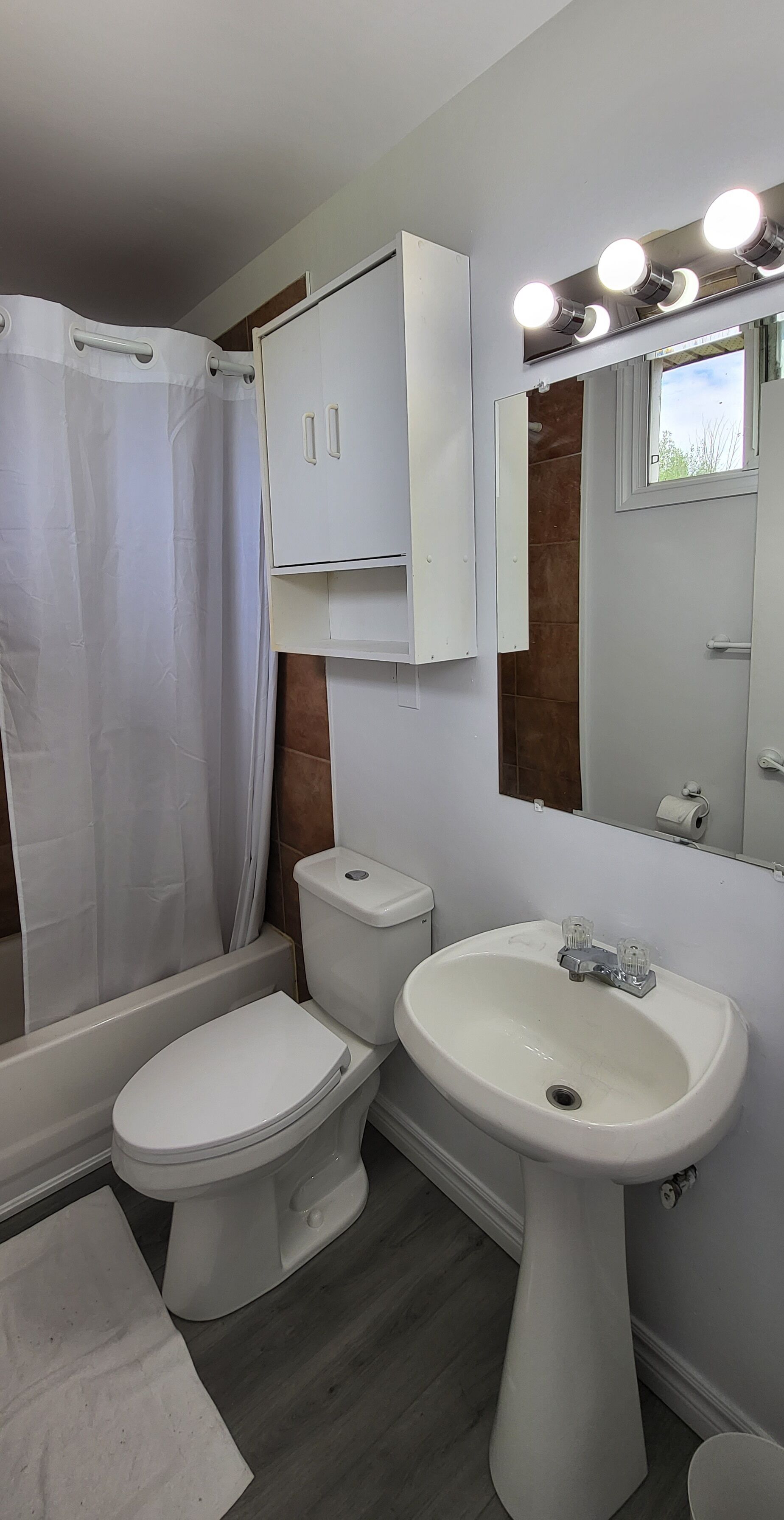A bathroom with a toilet, sink, and shower area.