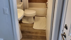 A bathroom with a toilet, sink, and bathtub. - Happyland Inn (Severn)