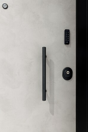 A modern door with a vertical handle, a keyhole, and a remote control. - Athens Theatrou Apartments (Athens)