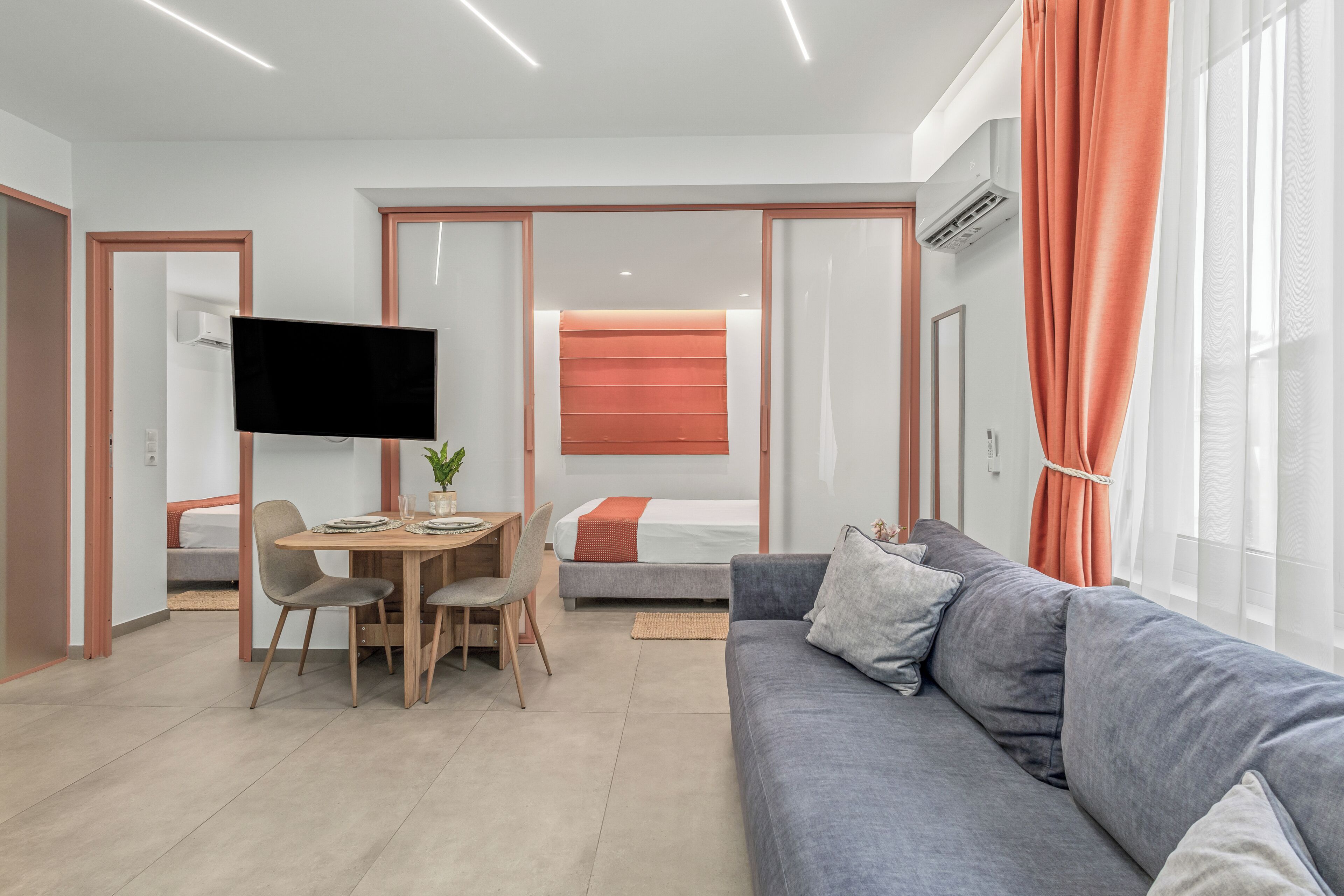 Een moderne woonkamer met een flatscreen televisie, een eettafel en een bank.