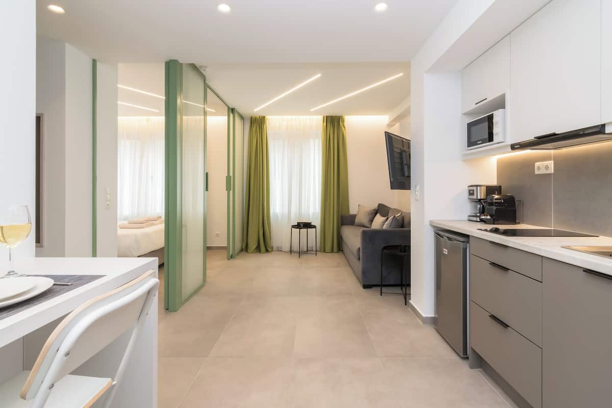 A modern hotel room with a kitchenette, a dining area, and a living space.