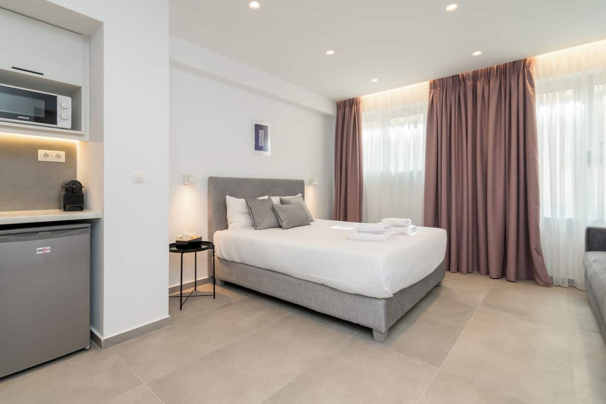 A modern hotel room with a bed, bedside table, and a built-in mini-fridge.