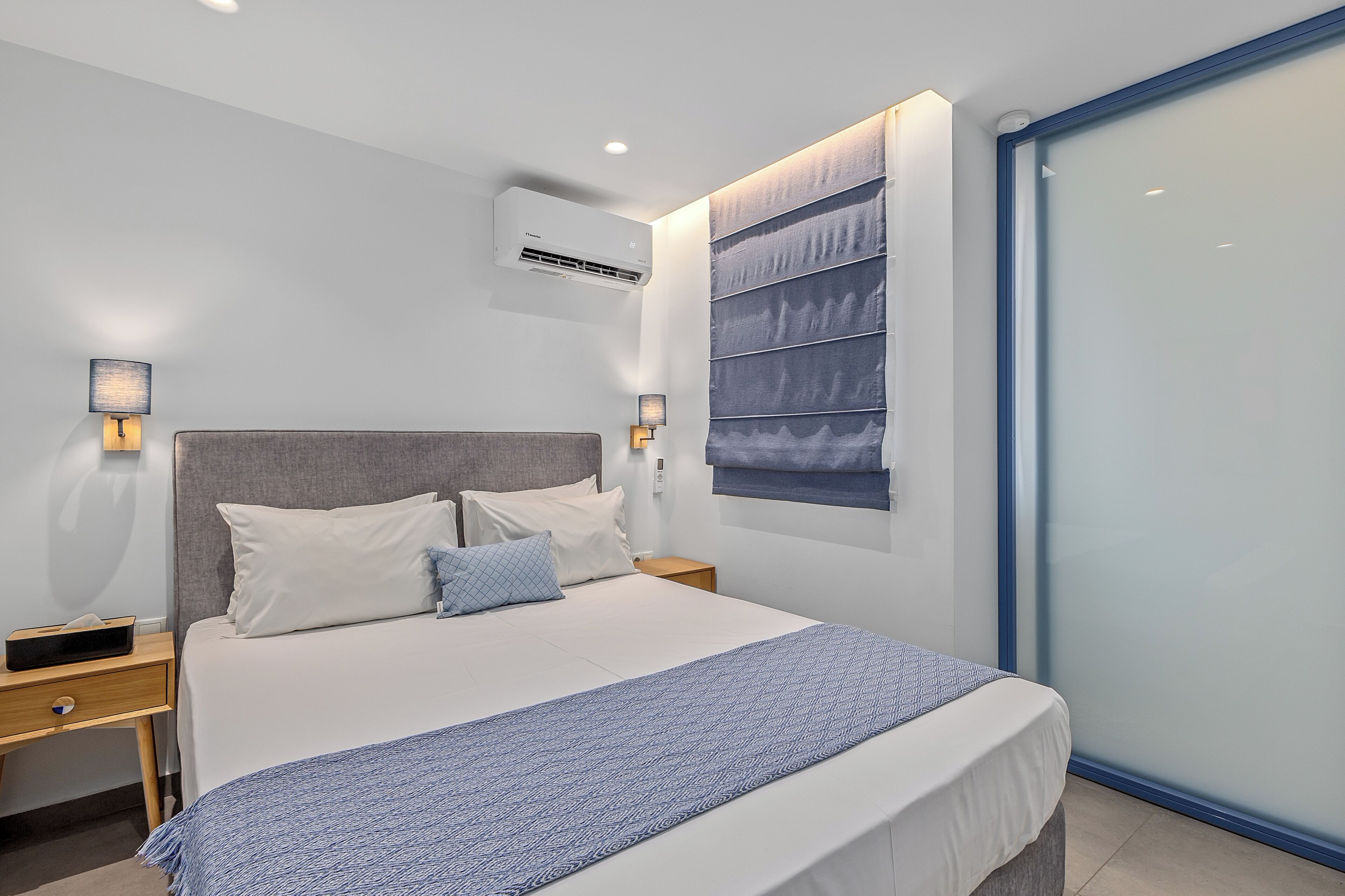 A modern bedroom with a bed, bedside tables, and a large window with a view.