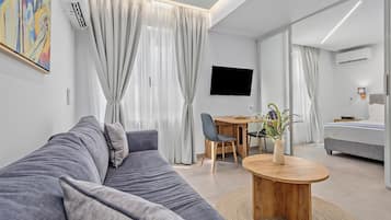 A modern living room with a grey sofa, a wooden coffee table, and a TV mounted on the wall.