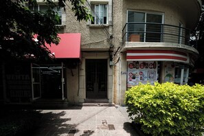 A building with a red awning, a balcony, and a door with a sign.
