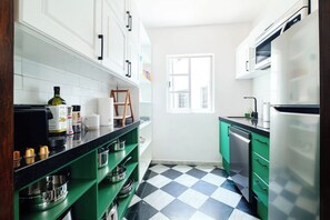 A kitchen with white cabinets, a black and white checkered floor, and green appliances.