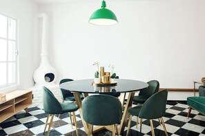 Zona pranzo con tavolo rotondo, sedie verdi e lampadario a sospensione verde.