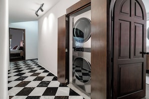 A hotel room with a checkered floor, a wooden door, and a washing machine.