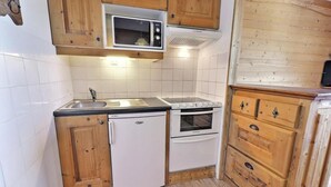 Una cocina funcional con armarios de madera, un microondas, un refrigerador y un horno.