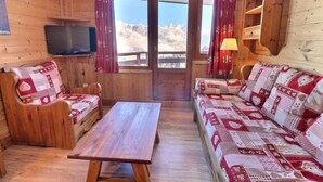 Una habitación acogedora de madera con un sofá, una mesa de madera y un televisor.
