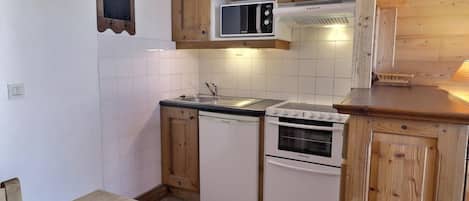 A compact kitchen with wooden cabinets, a microwave, a dishwasher, and an oven.
