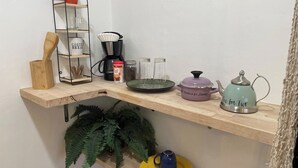 A kitchen shelf with a coffee maker, tea kettle, and various kitchen items. - Private Studio in the Heart of Coral Gables (Miami)
