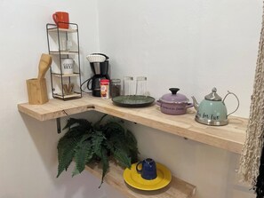 Une étagère de cuisine avec une machine à café, une bouilloire et divers ustensiles de cuisine.