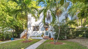 A white house with a front porch, palm trees, and a well-maintained lawn. - Private Studio in the Heart of Coral Gables (Miami)
