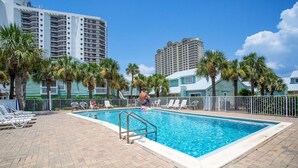 A swimming pool with a metal ladder, surrounded by lounge chairs and palm trees. - Sea Cabins 11D - Updated Beachside Cabin, Swimming Pool, Private Beach Access! (Miramar Beach)