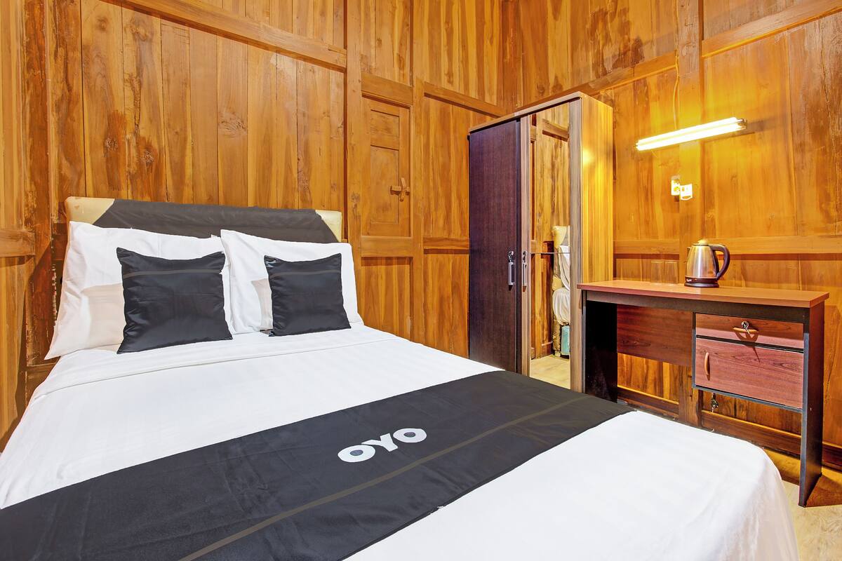 Una habitación con paneles de madera, una cama, un escritorio y un espejo.
