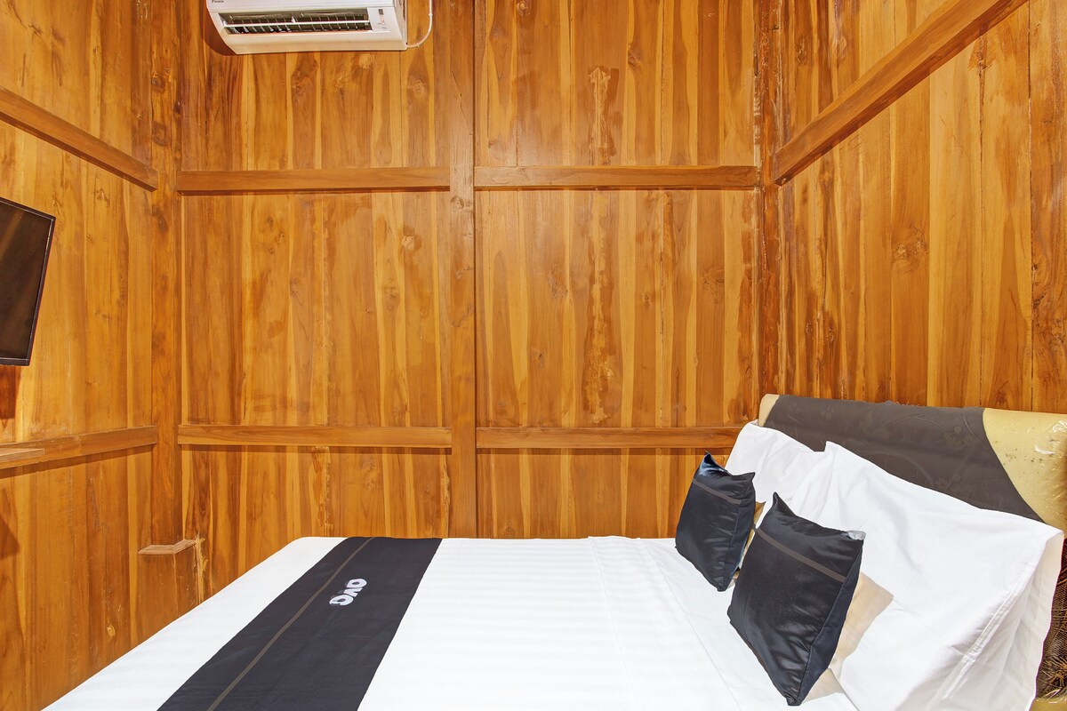 Ein Zimmer mit Holzwandverkleidung, einem Bett, Kissen und einer Wand-Klimaanlage.