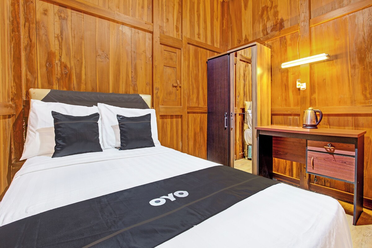 A wooden-paneled room with a bed, a desk, and a nightstand.