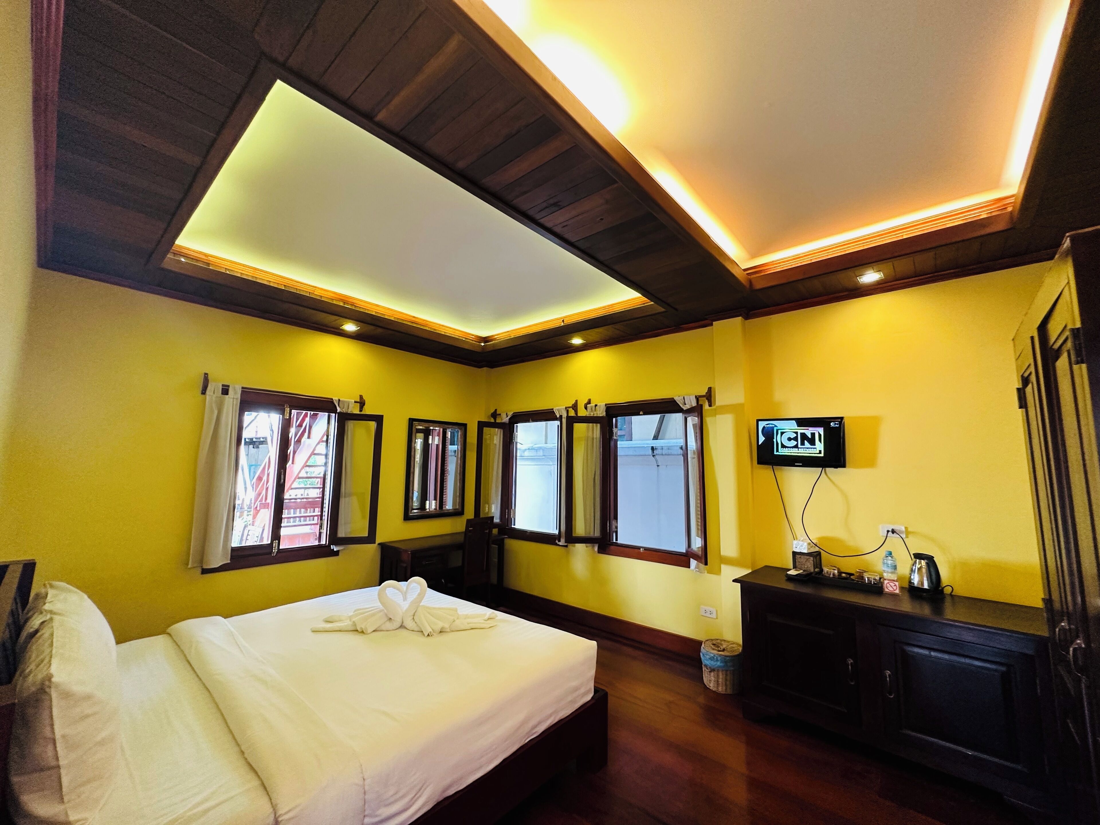 A hotel room with a bed, a TV, and a desk with a coffee maker.