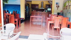 A restaurant with wooden furniture, a kitchen area, and a mural of a blue sky and sea. - Villa Phonethip Mekong Riverside (Luang Prabang)