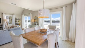 Ein geräumiges Wohnzimmer mit Holztisch, bequemen Sitzgelegenheiten und einem großen Fenster mit Blick ins Freie.