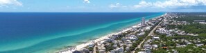 Vista aérea de uma cidade costeira com praia, edifícios residenciais e uma torre imponente.