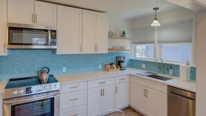 A kitchen with white cabinets, a stainless steel stove, a microwave, and a sink. - 1Nt. Ok, Walk to Beach and Town, Romantic, Firepit, BBQ (Bungalow2) (Ocean Park)