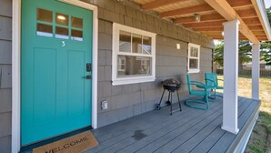 A house with a turquoise door, a porch with chairs, and a grill. - 1Nt. Ok, Walk to Beach and Town, Romantic, Firepit, BBQ (Bungalow3) (Ocean Park)