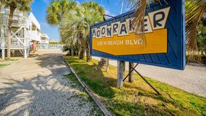 Señal de Moonriver Beach Blvd. con vista a un edificio y palmeras.