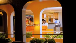 Un ristorante con vista sulla cucina, che mostra uno chef al lavoro, un computer e varie attrezzature da cucina.